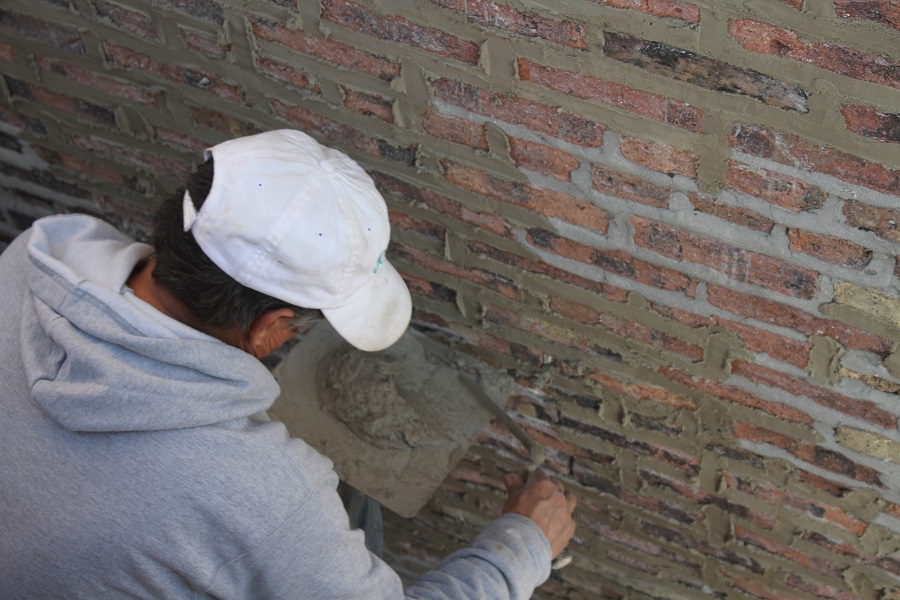 man applying plaster to brick wall