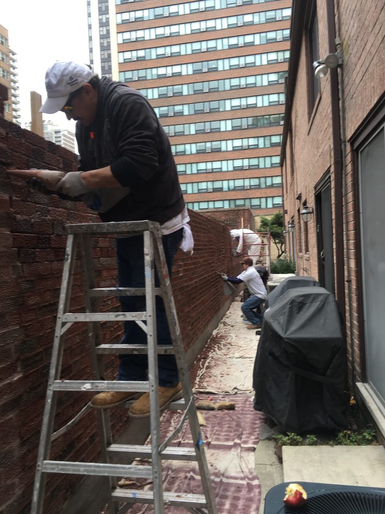 Man on ladder working on brick wall