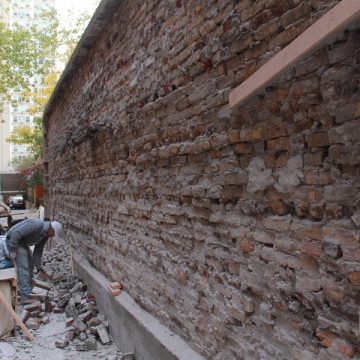 Man observing damaged brick wall