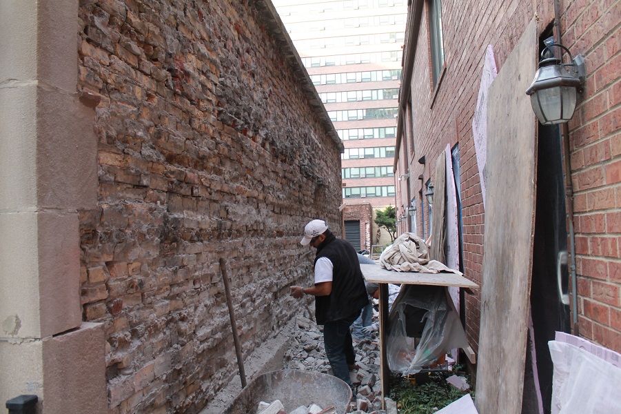 man working on damaged brick wall