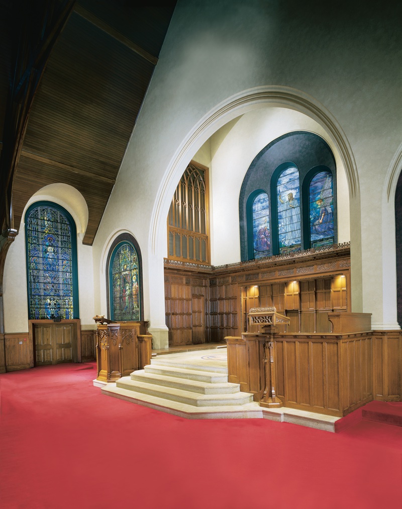 Restored chancel at First Presbyterian Church of Lake Forest with stained glass windows, carved wood paneling, and refinished plaster walls
