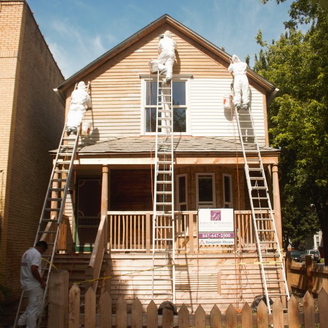 Fortune Restoration crew in lead-safe suits stripping exterior paint from the Walt Disney birthplace home front facade in Chicago