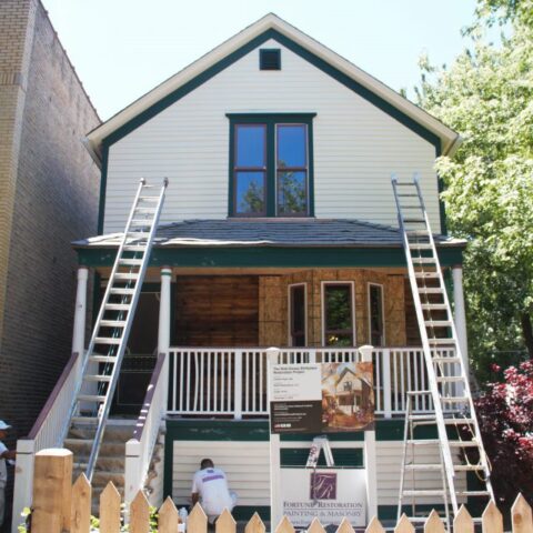 Walt Disney birthplace home mid-restoration with fresh cream and green exterior paint and ladders on the front porch in Chicago's Hermosa neighborhood