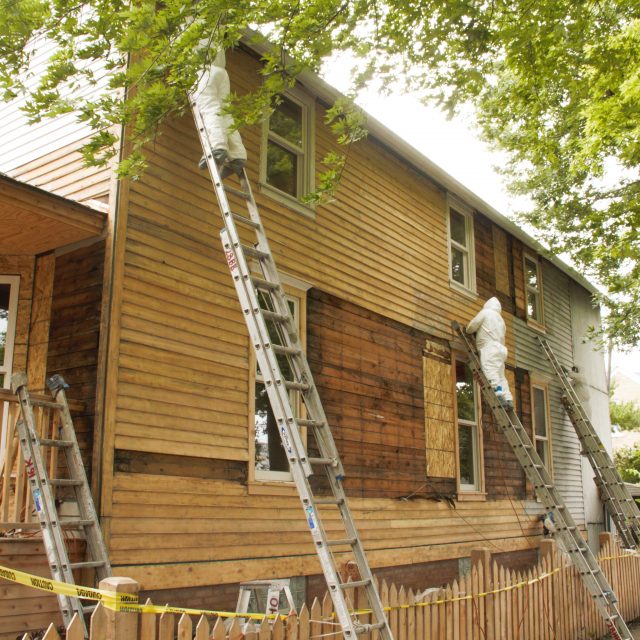 Fortune Restoration crew removing paint to expose original wood clapboard siding on the side elevation of the Walt Disney birthplace home in Chicago