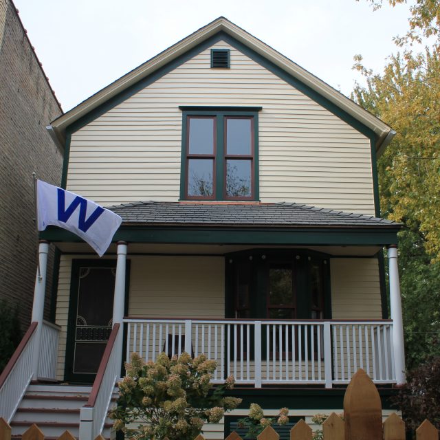 Completed exterior restoration of the Walt Disney birthplace home showing cream clapboard siding, green trim, and restored front porch in Chicago